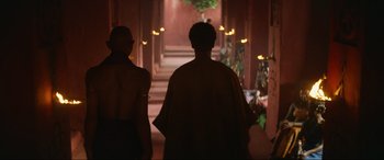 Movie still from “The Woman King” (2022), directed by Gina Prince-Bythewood – Two people are walking in a hallway with lights on; Wide shot, Over the shoulder angle