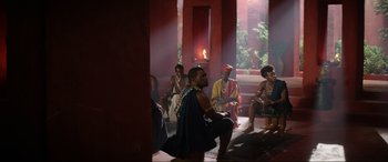 Movie still from “The Woman King” (2022), directed by Gina Prince-Bythewood – A group of people sitting in a room with a fire in the background; Wide shot, Over the shoulder angle