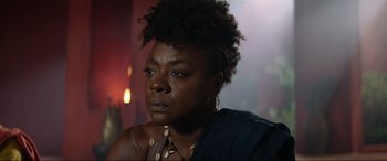 Movie still from “The Woman King” (2022), directed by Gina Prince-Bythewood – A person wearing a necklace and looking at the camera; Close Up shot, Over the shoulder angle