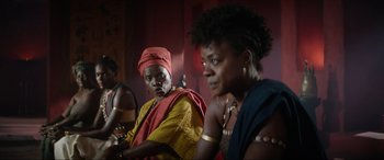 Movie still from “The Woman King” (2022), directed by Gina Prince-Bythewood – A couple of women sitting next to each other in a room; Medium shot, Over the shoulder angle