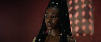 Movie still from “The Woman King” (2022), directed by Gina Prince-Bythewood – A beautiful young woman with long black braids; Close Up shot, Over the shoulder angle