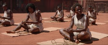 Movie still from “The Woman King” (2022), directed by Gina Prince-Bythewood – A group of people sitting on the ground; Medium shot, High angle
