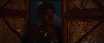 Movie still from “The Woman King” (2022), directed by Gina Prince-Bythewood – A woman with a head scarf looking out of a window; Close Up shot, Over the shoulder angle