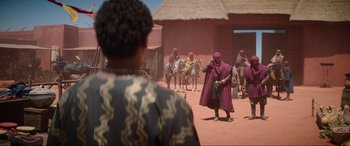 Movie still from “The Woman King” (2022), directed by Gina Prince-Bythewood – A group of people riding horses on a dirt road; Wide shot, Over the shoulder angle