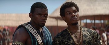 Movie still from “The Woman King” (2022), directed by Gina Prince-Bythewood – A couple of men standing next to each other; Close Up shot, Low angle