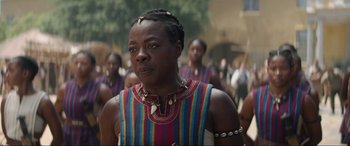 Movie still from “The Woman King” (2022), directed by Gina Prince-Bythewood – A group of men in colorful clothing standing next to each other; Close Up shot, Over the shoulder angle