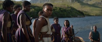 Movie still from “The Woman King” (2022), directed by Gina Prince-Bythewood – A group of people standing next to a body of water; Medium shot, Over the shoulder angle
