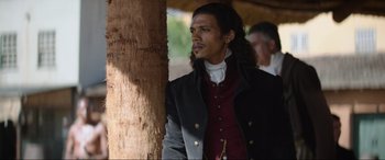 Movie still from “The Woman King” (2022), directed by Gina Prince-Bythewood – A man standing next to a tree looking off into the distance; Close Up shot, Over the shoulder angle