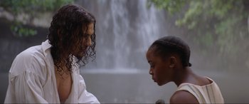 Movie still from “The Woman King” (2022), directed by Gina Prince-Bythewood – A man and a woman facing each other in front of a waterfall; Medium shot, Over the shoulder angle