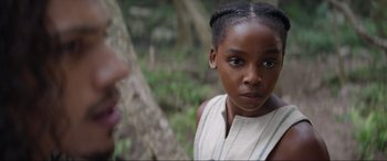 Movie still from “The Woman King” (2022), directed by Gina Prince-Bythewood – A young black girl standing in front of a tree; Close Up shot, Over the shoulder angle