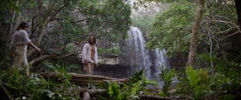 Movie still from “The Woman King” (2022), directed by Gina Prince-Bythewood – A man standing in front of a waterfall in the woods; Wide shot, Low angle