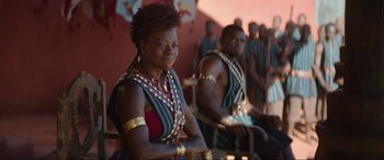Movie still from “The Woman King” (2022), directed by Gina Prince-Bythewood – A couple of people that are sitting down; Medium shot, Over the shoulder angle