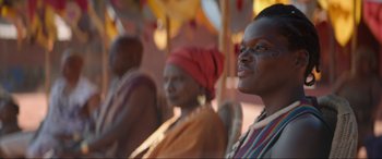 Movie still from “The Woman King” (2022), directed by Gina Prince-Bythewood – A group of people sitting next to each other; Close Up shot, Over the shoulder angle