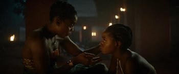 Movie still from “The Woman King” (2022), directed by Gina Prince-Bythewood – A woman touching the face of a young girl; Close Up shot, Over the shoulder angle
