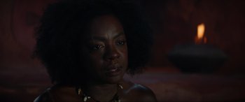 Movie still from “The Woman King” (2022), directed by Gina Prince-Bythewood – A person wearing a necklace; Close Up shot, Over the shoulder angle