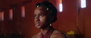 Movie still from “The Woman King” (2022), directed by Gina Prince-Bythewood – A young woman with a bunch of seashells in her hair; Close Up shot, Low angle
