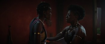 Movie still from “The Woman King” (2022), directed by Gina Prince-Bythewood – Two women are talking to each other in a dark room; Close Up shot, Over the shoulder angle