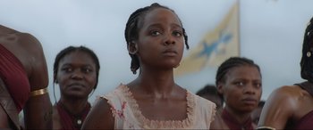 Movie still from “The Woman King” (2022), directed by Gina Prince-Bythewood – A young girl is looking up into the sky; Close Up shot, Low angle