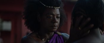 Movie still from “The Woman King” (2022), directed by Gina Prince-Bythewood – A woman in a purple dress and a necklace; Close Up shot, Over the shoulder angle