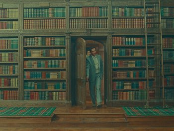Movie still from “The Wonderful Story of Henry Sugar” (2023), directed by Wes Anderson – A man standing in front of a book shelf; Wide shot, High angle