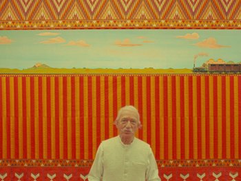 Movie still from “The Wonderful Story of Henry Sugar” (2023), directed by Wes Anderson – An older man standing in front of a painting; Medium shot, Low angle