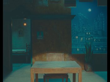 Movie still from “The Wonderful Story of Henry Sugar” (2023), directed by Wes Anderson – A wooden table and chairs in a room; Wide shot, High angle