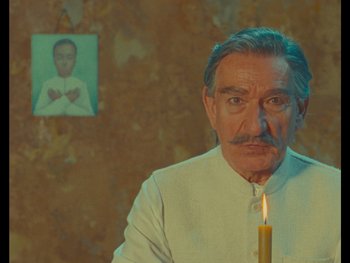 Movie still from “The Wonderful Story of Henry Sugar” (2023), directed by Wes Anderson – An older man with a mustache and a candle in front of him; Close Up shot, Low angle