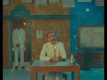 Movie still from “The Wonderful Story of Henry Sugar” (2023), directed by Wes Anderson – A man sitting at a table with a candle in front of him; Wide shot, Over the shoulder angle
