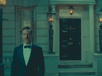 Movie still from “The Wonderful Story of Henry Sugar” (2023), directed by Wes Anderson – A man standing in front of a door way; Wide shot, Over the shoulder angle