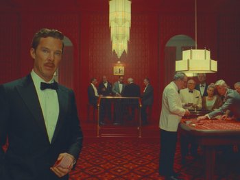 Movie still from “The Wonderful Story of Henry Sugar” (2023), directed by Wes Anderson – A group of people in a room with a man in a tuxedo; Wide shot, High angle