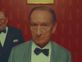 Movie still from “The Wonderful Story of Henry Sugar” (2023), directed by Wes Anderson – An older man in a suit and bow tie; Close Up shot, Low angle