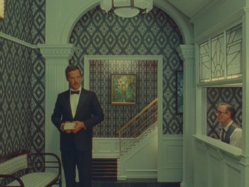 Movie still from “The Wonderful Story of Henry Sugar” (2023), directed by Wes Anderson – A man in a tuxedo standing in front of a staircase; Wide shot, Low angle
