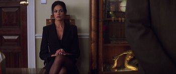 Movie still from “The World Is Not Enough” (1999), directed by Michael Apted – A woman sitting in front of a wooden cabinet; Medium shot, Low angle