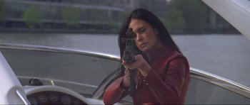 Movie still from “The World Is Not Enough” (1999), directed by Michael Apted – A woman in a red leather jacket holding a gun; Close Up shot, Low angle