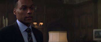 Movie still from “The World Is Not Enough” (1999), directed by Michael Apted – A person wearing a suit in a room; Close Up shot, Over the shoulder angle