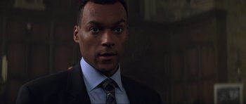 Movie still from “The World Is Not Enough” (1999), directed by Michael Apted – A person wearing a suit and tie; Close Up shot, Over the shoulder angle