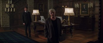 Movie still from “The World Is Not Enough” (1999), directed by Michael Apted – An older woman standing in front of two lamps in a room; Wide shot, Low angle