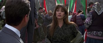 Movie still from “The World Is Not Enough” (1999), directed by Michael Apted – A beautiful woman in a green dress standing in front of a group of people; Close Up shot, Over the shoulder angle