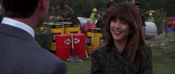 Movie still from “The World Is Not Enough” (1999), directed by Michael Apted – A woman smiles in front of a group of people; Medium shot, Over the shoulder angle