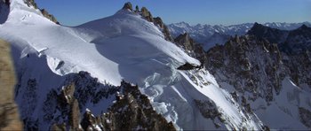 Movie still from “The World Is Not Enough” (1999), directed by Michael Apted – A helicopter is flying over a snowy mountain; Extreme Wide shot, High angle
