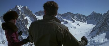 Movie still from “The World Is Not Enough” (1999), directed by Michael Apted – A man standing on top of a snow covered slope; Extreme Wide shot, High angle