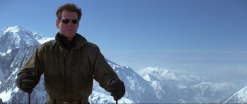 Movie still from “The World Is Not Enough” (1999), directed by Michael Apted – A man holding a ski pole on top of a snow covered slope; Medium shot, Low angle
