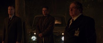 Movie still from “The World Is Not Enough” (1999), directed by Michael Apted – Two men standing in front of a car at night; Medium shot, Low angle