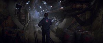 Movie still from “The World Is Not Enough” (1999), directed by Michael Apted – A man standing in a train tunnel looking at the lights; Wide shot, High angle