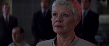 Movie still from “The World Is Not Enough” (1999), directed by Michael Apted – An older woman with short blonde hair looking at the camera; Close Up shot, Low angle