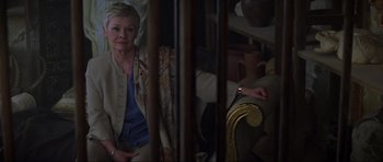 Movie still from “The World Is Not Enough” (1999), directed by Michael Apted – An older woman sitting on a chair in a room; Medium shot, High angle