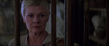 Movie still from “The World Is Not Enough” (1999), directed by Michael Apted – An older woman with short blonde hair looking at the camera; Close Up shot, Low angle