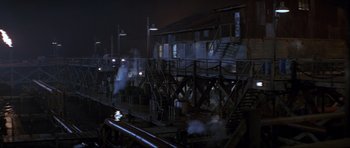 Movie still from “The World Is Not Enough” (1999), directed by Michael Apted – Steam rises out of a building at night; Extreme Wide shot, High angle