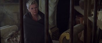 Movie still from “The World Is Not Enough” (1999), directed by Michael Apted – An older woman sitting in a chair in front of a mirror; Medium shot, High angle