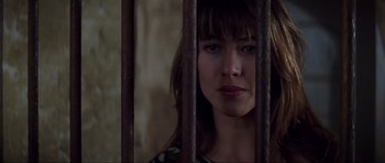 Movie still from “The World Is Not Enough” (1999), directed by Michael Apted – A woman standing behind a metal fence looking at the camera; Close Up shot, Low angle